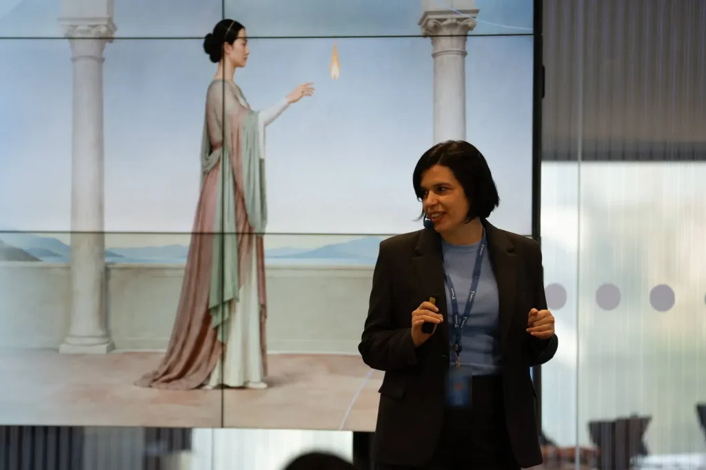 Irene Ferrer, ponente en Telefónica Creators 2026, durante su charla con una ilustración de inspiración clásica proyectada al fondo.