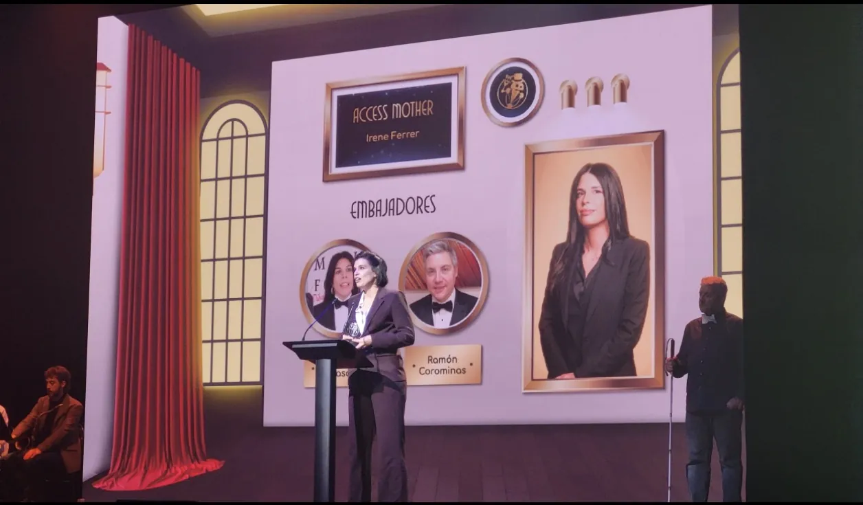 Irene Ferrer en el atril del escenario de la Gala de Sirviendo Código 2026, ante la pantalla que la anuncia ganadora del premio Access Mother.